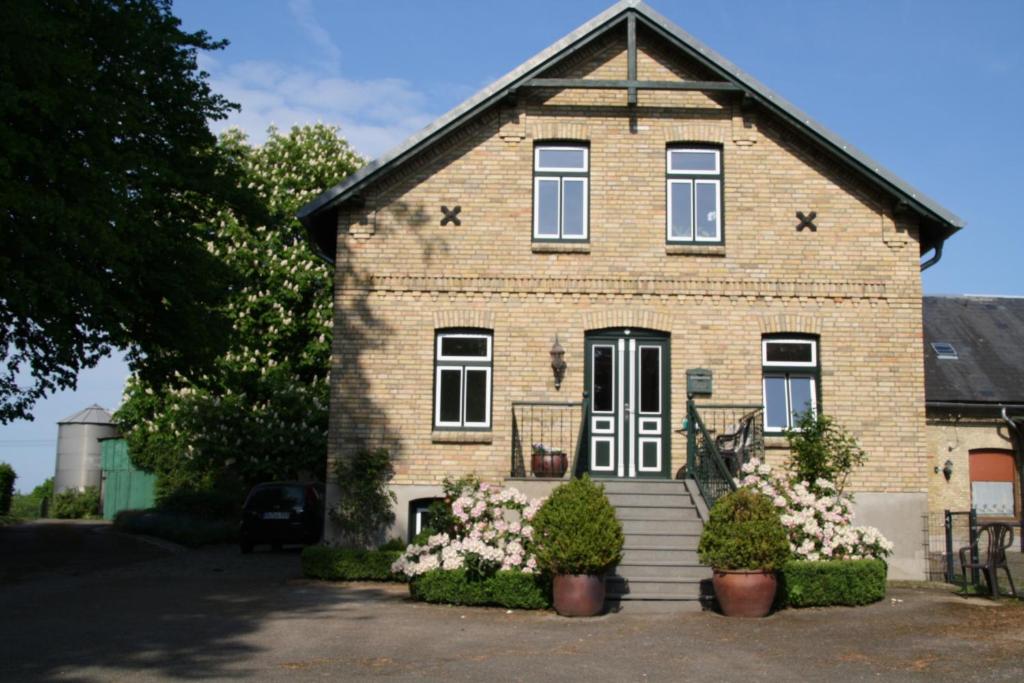 une maison en briques avec des fleurs devant elle dans l'établissement Ferienwohnung Am Ochsenweg, à Hüsby