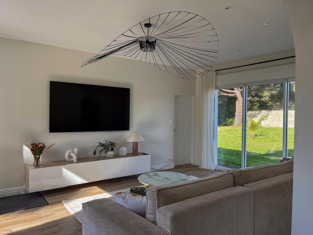 un salon avec un canapé et une télévision à écran plat dans l'établissement Villa de charme à 100 m de la mer, à Saint-Palais-sur-Mer