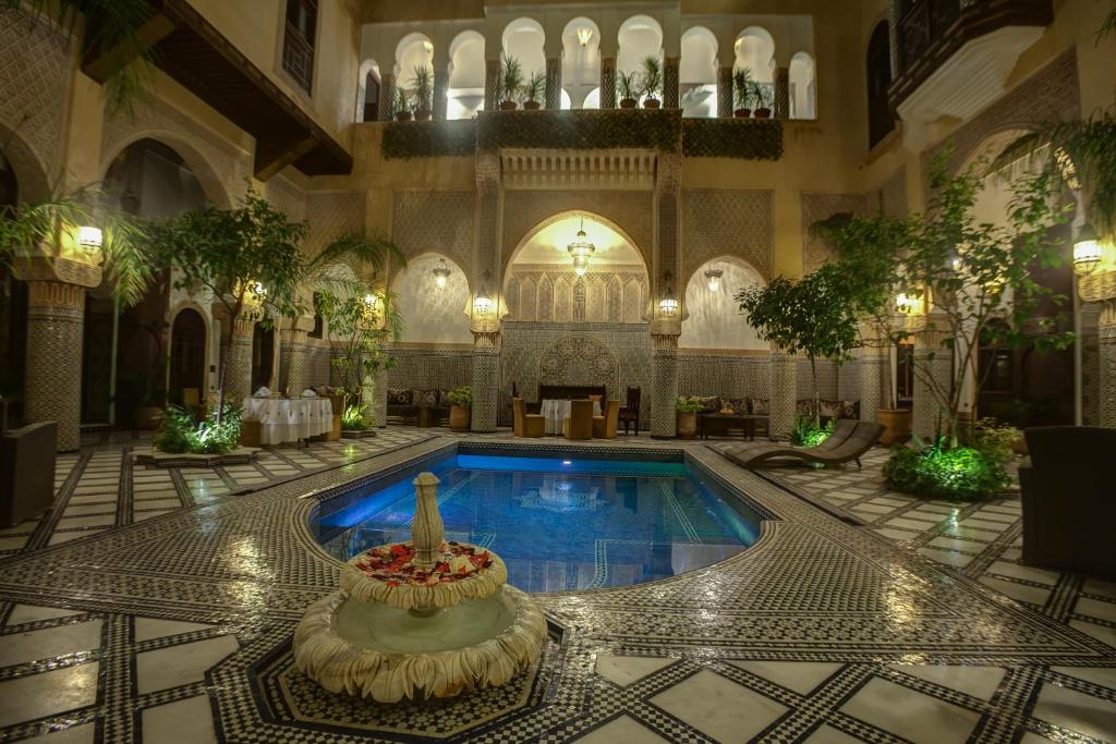 a pool in a building with a fountain in the middle at Riad Salam Fes in Fez
