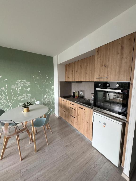 une cuisine avec une table blanche, une table, une table et des chaises dans l'établissement Le studio du lac Saint-Point, à Malbuisson