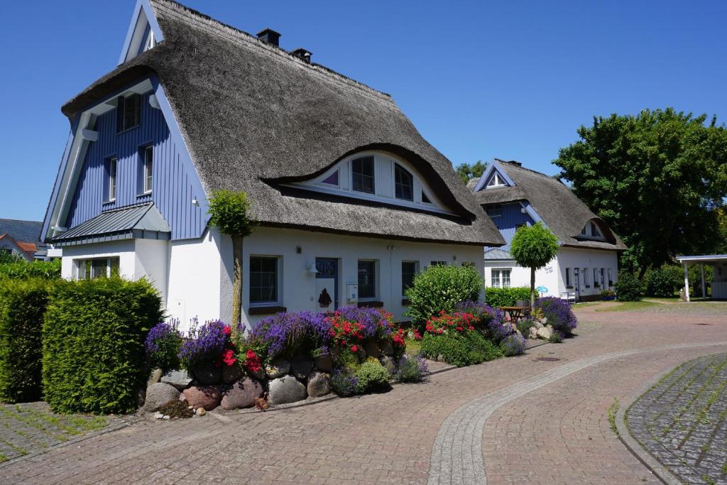 a white house with a thatched roof and flowers at Kranich in Zingst