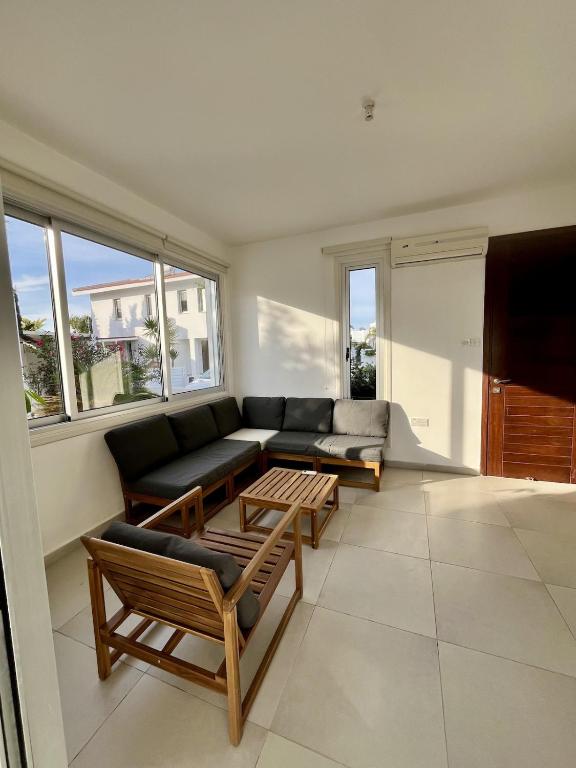 a living room with a couch and tables and windows at Luxury Villa Azure in Larnaca