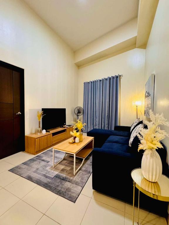 a living room with a blue couch and a tv at Opulent Spacious 3 BR Condominium at St Dominique at Megaworld in Iloilo City