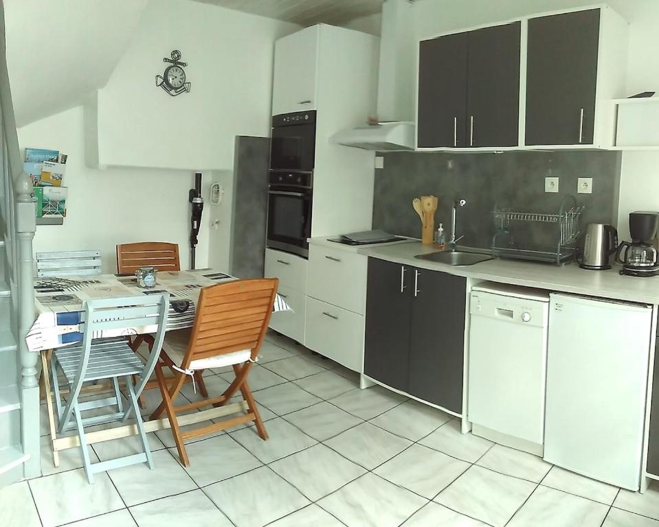 une cuisine avec des armoires blanches et une table et des chaises dans l'établissement Cap en vue, à Fécamp