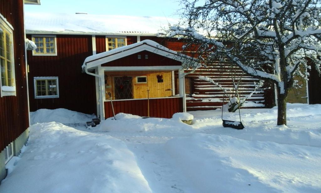 ein rotes Haus mit einer Holztür im Schnee in der Unterkunft Dränggårdens Stuga på Genuin Rättviksgård in Boda