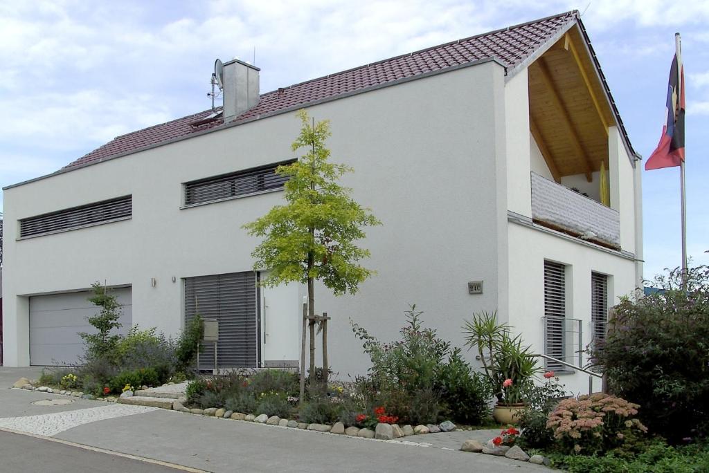 una casa blanca con un árbol delante en Ferienwohnung Bania, en Lindau-Bodolz