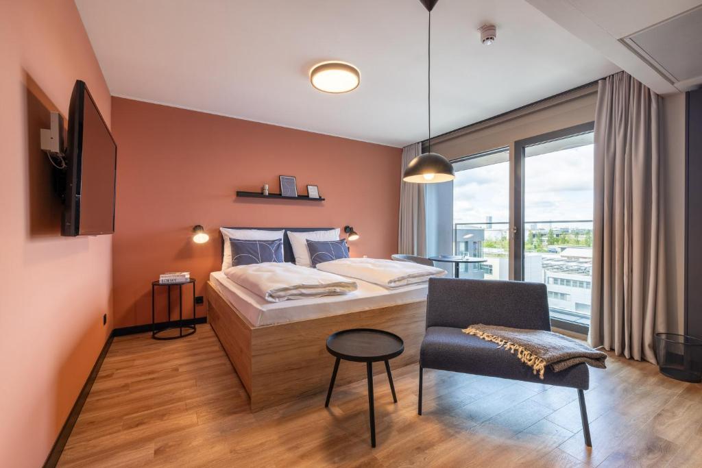 a bedroom with a bed and a chair and a window at The Base Munich in Munich