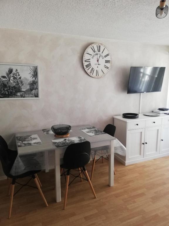 une salle à manger avec une table et une horloge au mur dans l'établissement Appartement avec balcon au centre de Saint-Lary, à Saint-Lary-Soulan