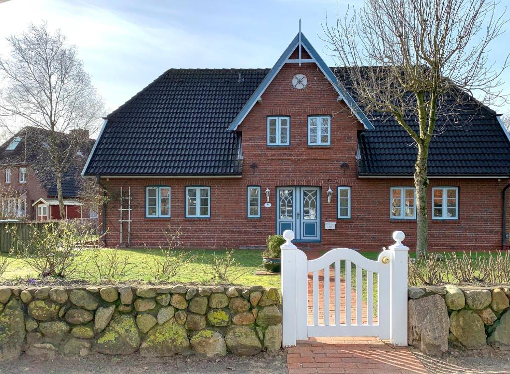 a red brick house with a white fence in front of it at Gmelinstrasse 33 in Wyk auf Föhr