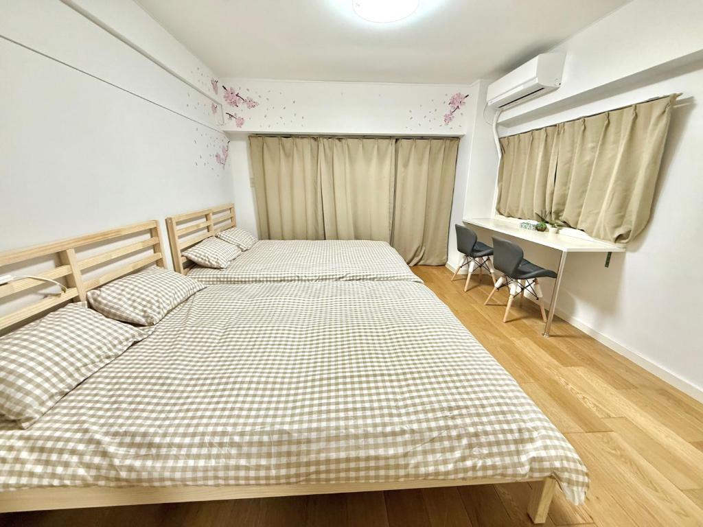 two beds in a small room with a desk and a window at Shinjuku Wasedaハウス T4 in Tokyo