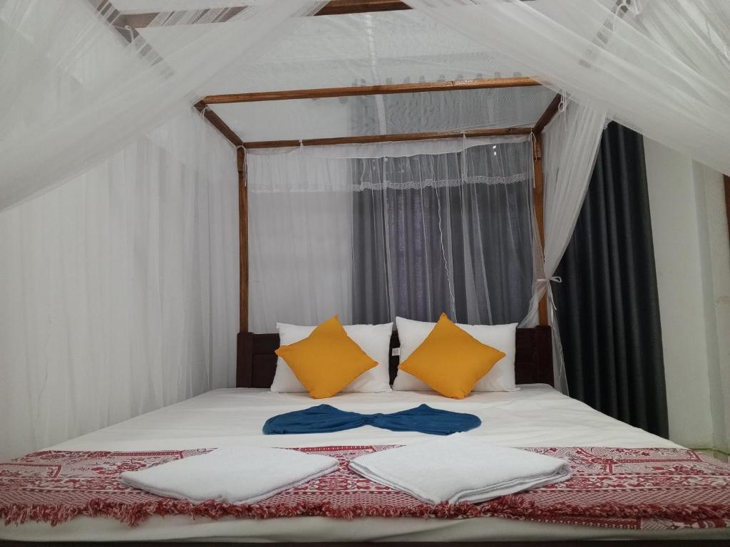 ein Schlafzimmer mit einem Bett mit gelben und weißen Kissen in der Unterkunft Villa Lumina Unawatuna in Galle