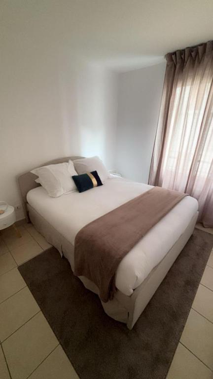 Cette chambre blanche dispose d'un grand lit et d'une fenêtre. dans l'établissement Élixir, à Villeurbanne