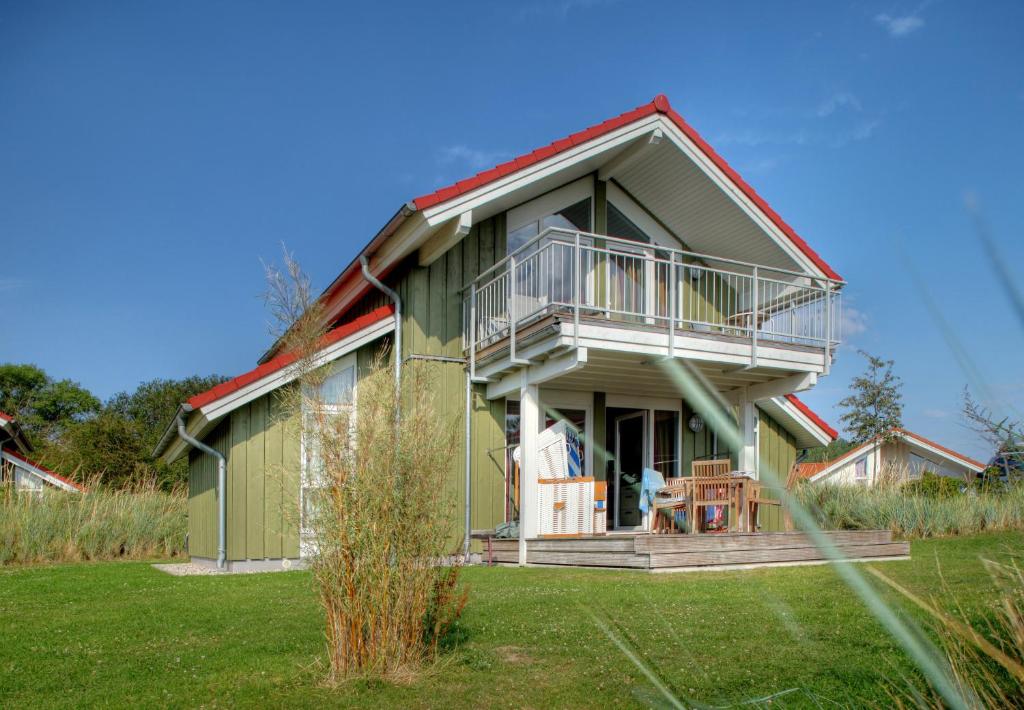 a green house with a porch and a balcony at Typ F "John Flint" -Kapitänshaus- in Pelzerhaken