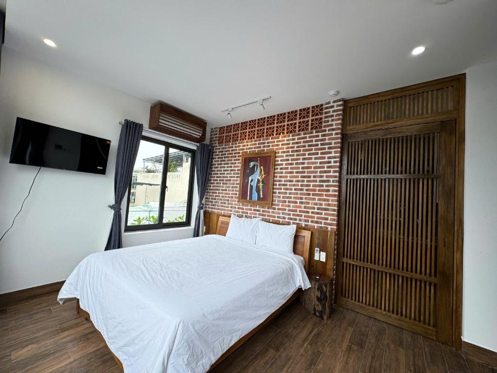 a bedroom with a white bed and a brick wall at CHAMECO ART Boutique Home Danang in Da Nang