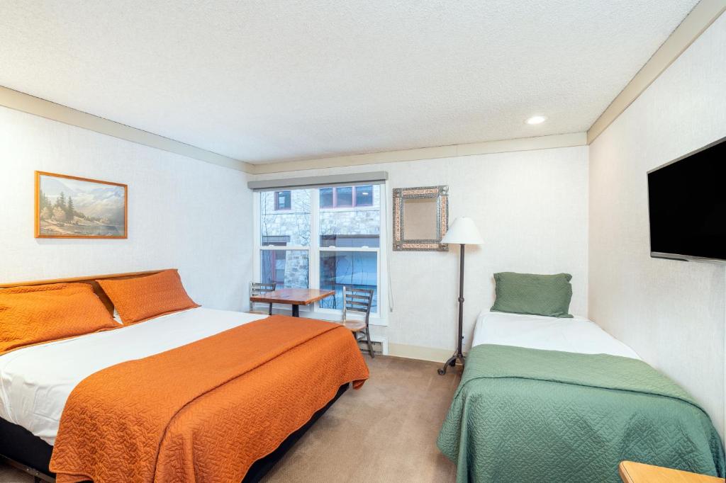 a hotel room with two beds and a television at Mountainside Inn 301 by Alpine Lodging Telluride in Telluride