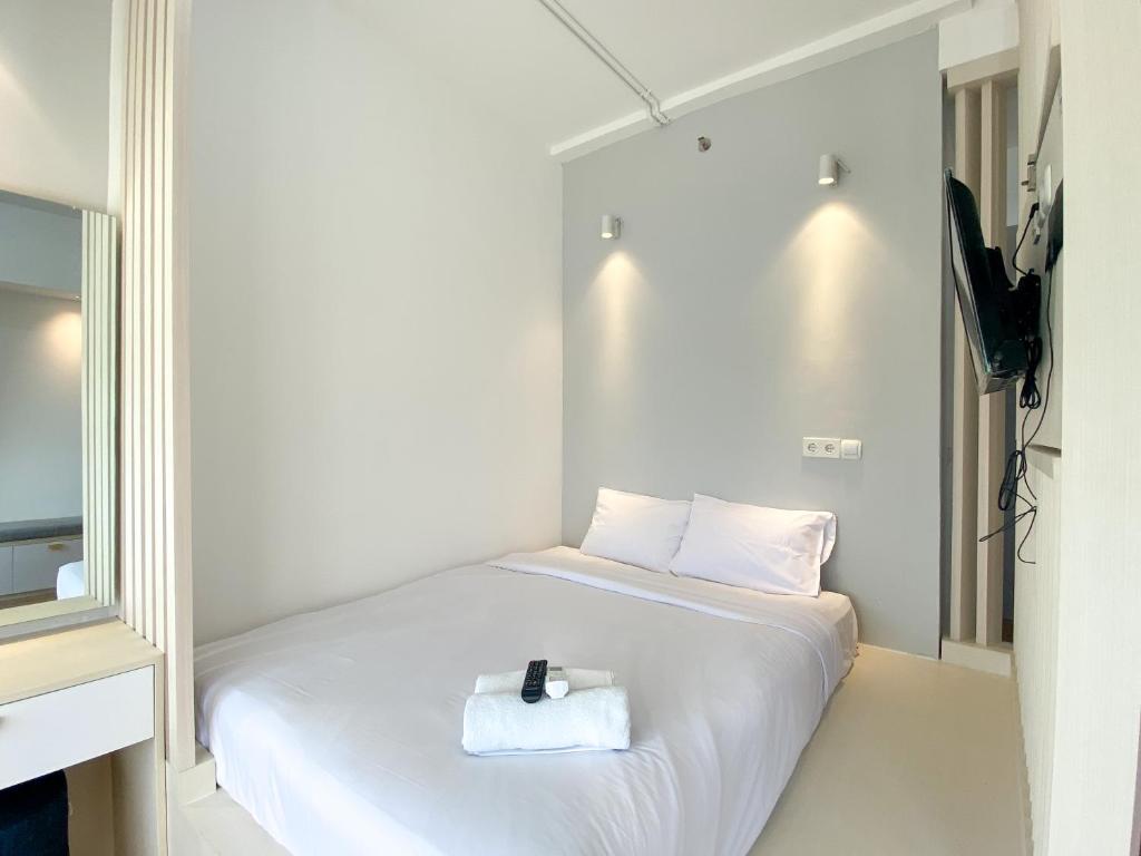 a bedroom with a white bed with a towel on it at Homey and Elegant Studio Vasanta Innopark Apartment By Travelio in Cikarang
