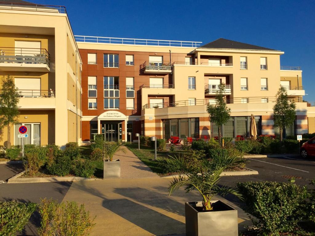 an apartment building with trees in front of it at Domitys Le Côteau d'Argent in Saint-Doulchard