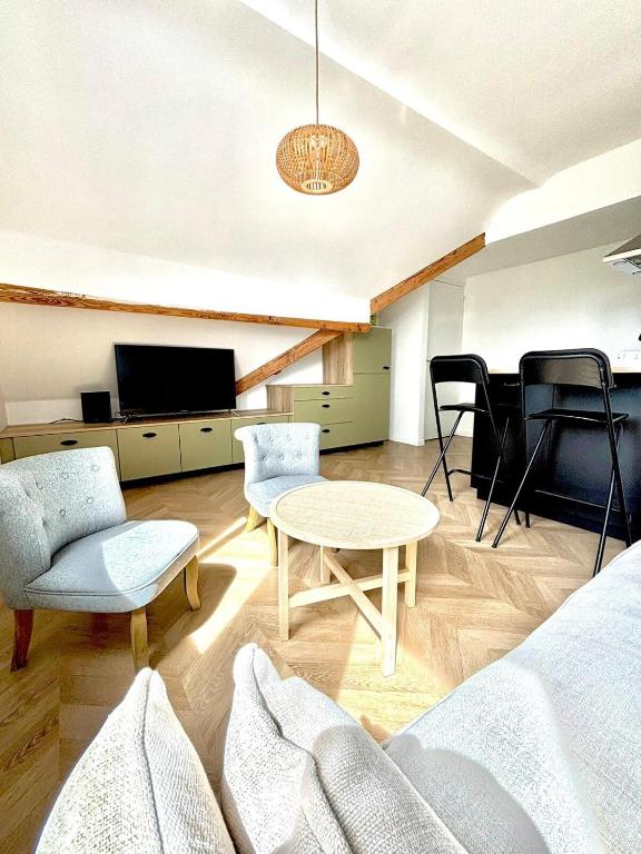 un salon avec une table, des chaises et une télévision dans l'établissement Studio Maya, à Donville-les-Bains