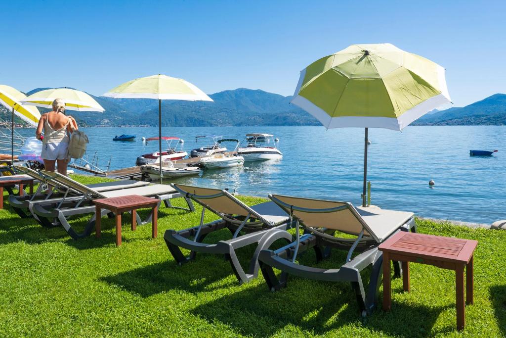a group of chairs and umbrellas next to a lake at Residence Casa e Vela in Oggebbio