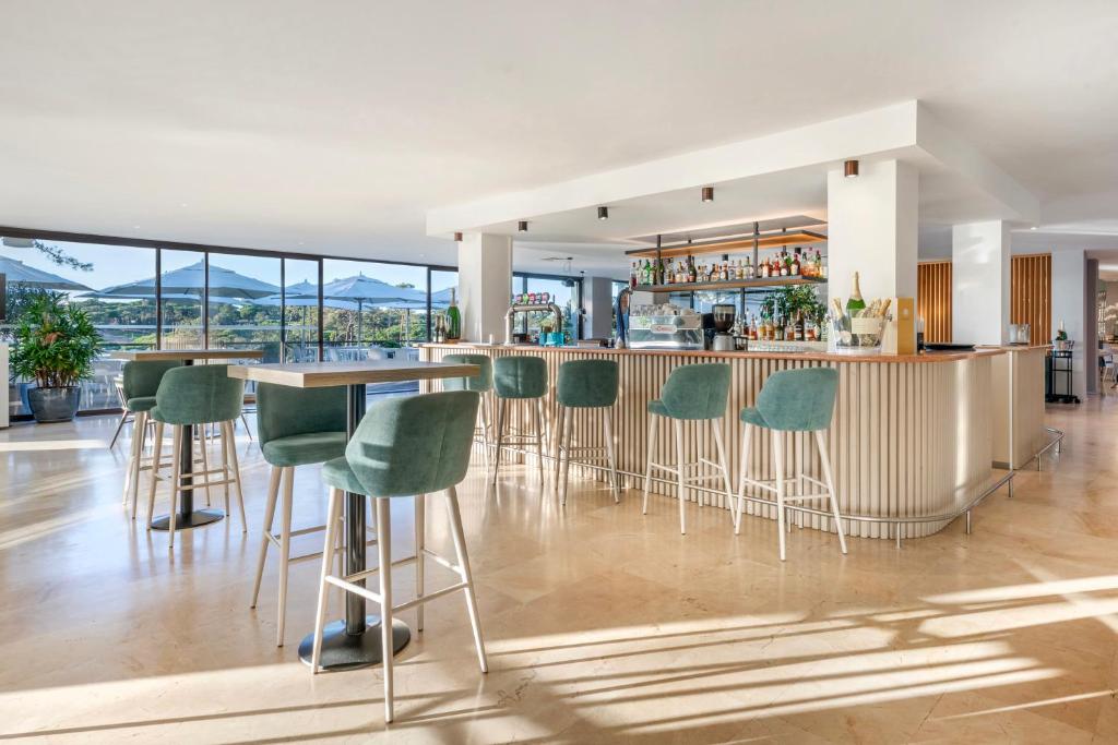 a bar with green chairs in a room with a view at Vilar do Golf in Quinta do Lago