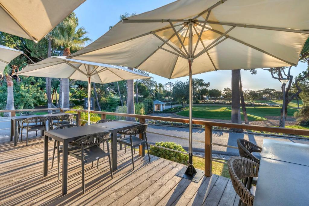 a deck with tables and chairs and umbrellas at Vilar do Golf in Quinta do Lago