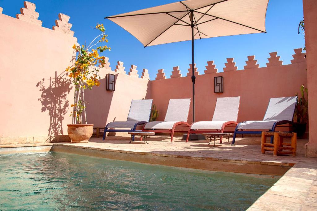 a group of chairs and an umbrella next to a pool at RIAD PRIVATIF avec Piscine Chauffée au Cœur de la Médina et Petits-Déjeuners Inclus in Marrakech