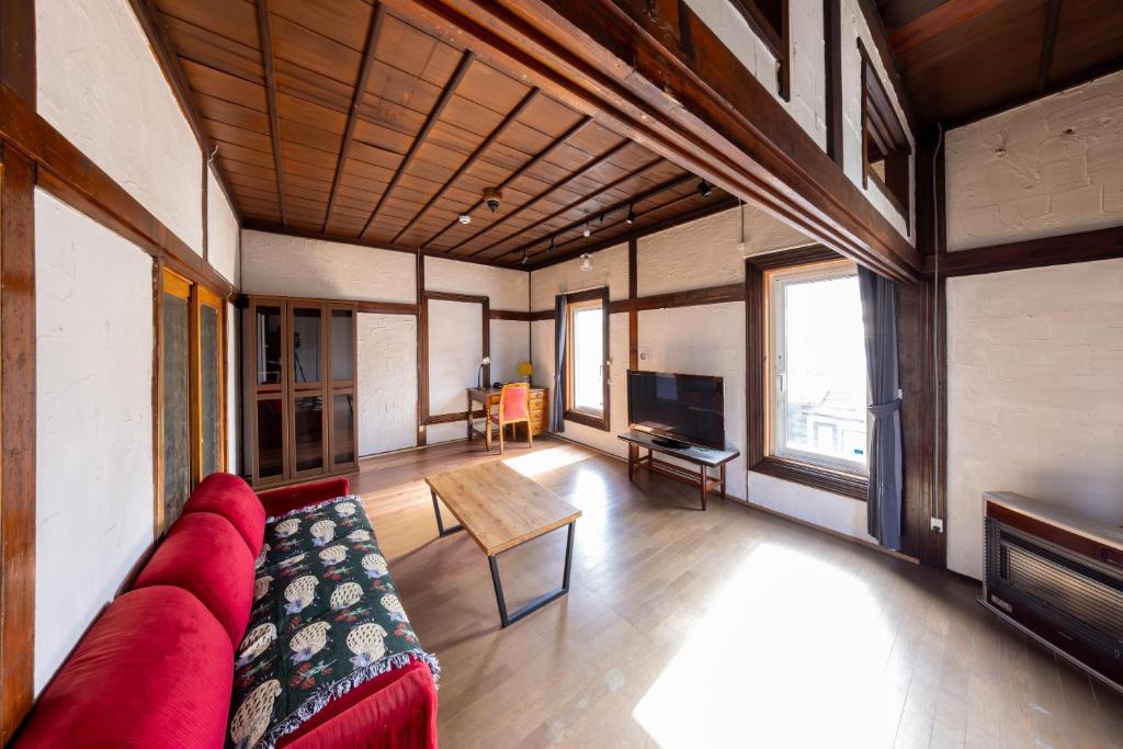Una sala de estar con un sofá rojo y una mesa. en Ura Otaru Montparnasse Inn, en Otaru