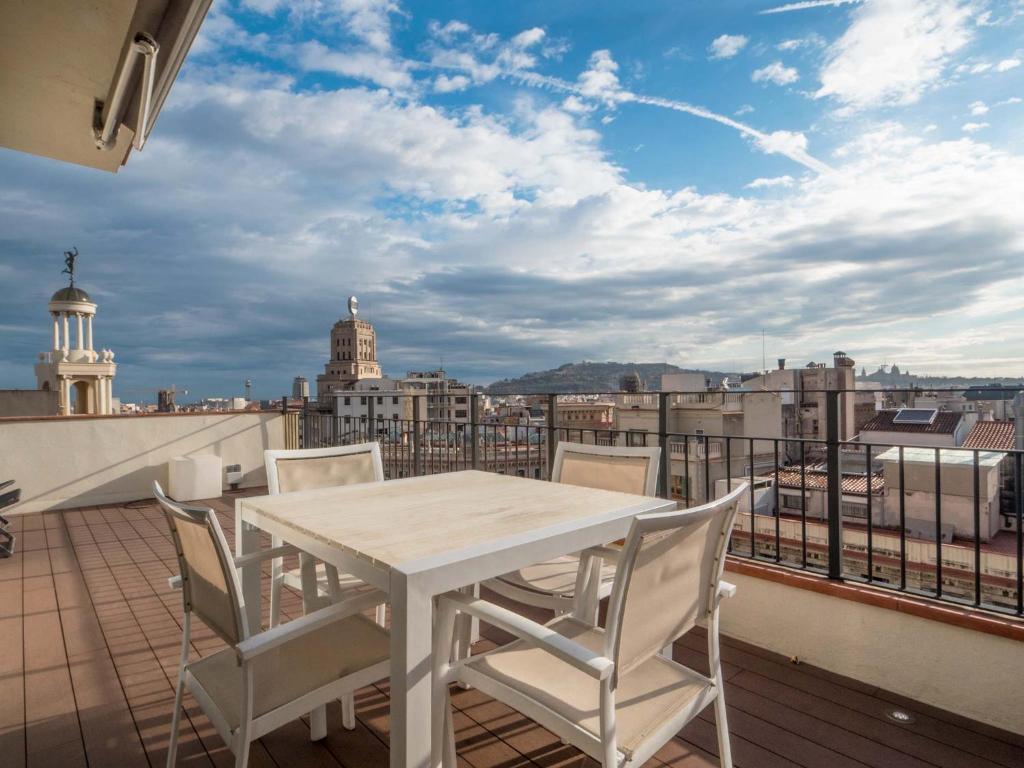 a white table and chairs on a balcony with a view at Rent Top Apartments Rambla Catalunya in Barcelona