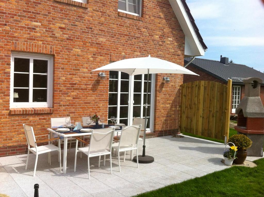 eine Terrasse mit Tisch und Sonnenschirm in der Unterkunft Lillebroo in Boldixum