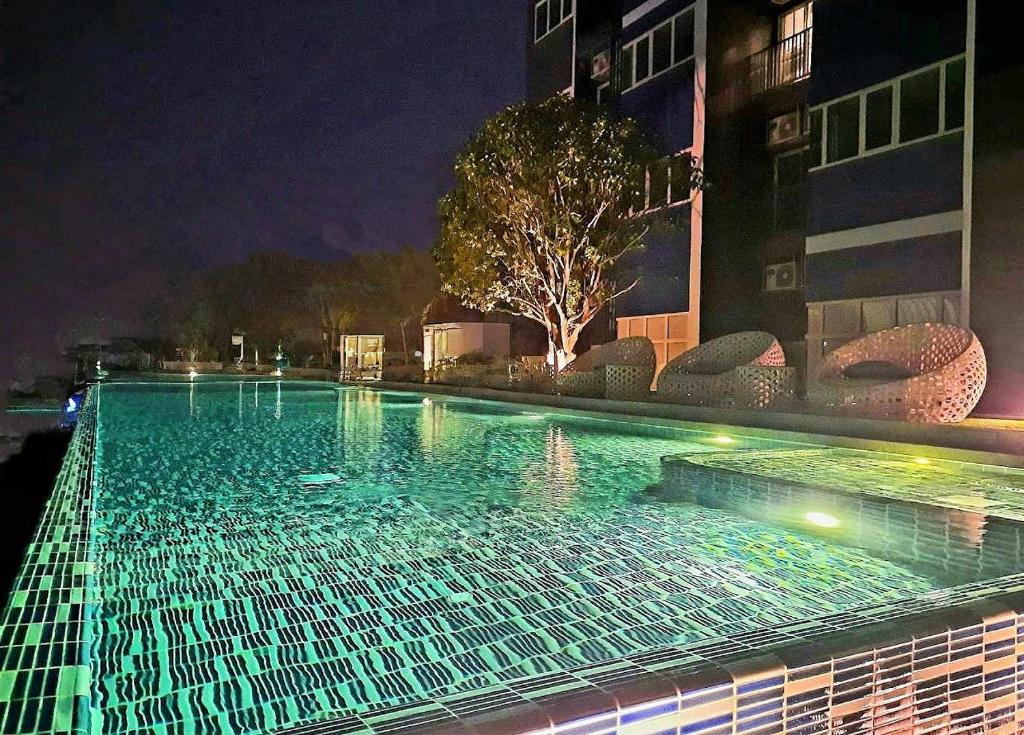 una gran piscina por la noche con un edificio en อพาร์ตเม้นต์แสนสงบ, en Thonhuri