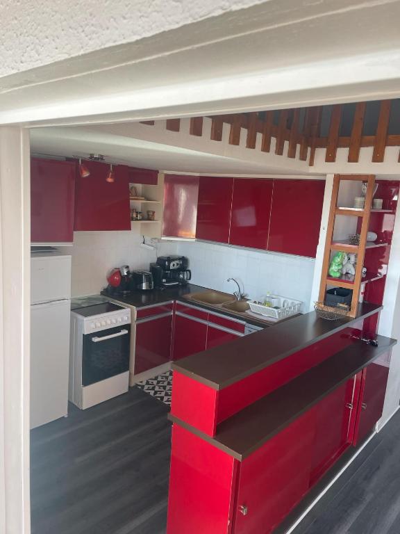 une cuisine avec des armoires rouges et un comptoir noir dans l'établissement F3 NARBONE-PLAGE AVEC SOLARIUM 250M DE LA MER VUE MER ET CLAPE, à Narbonne-Plage