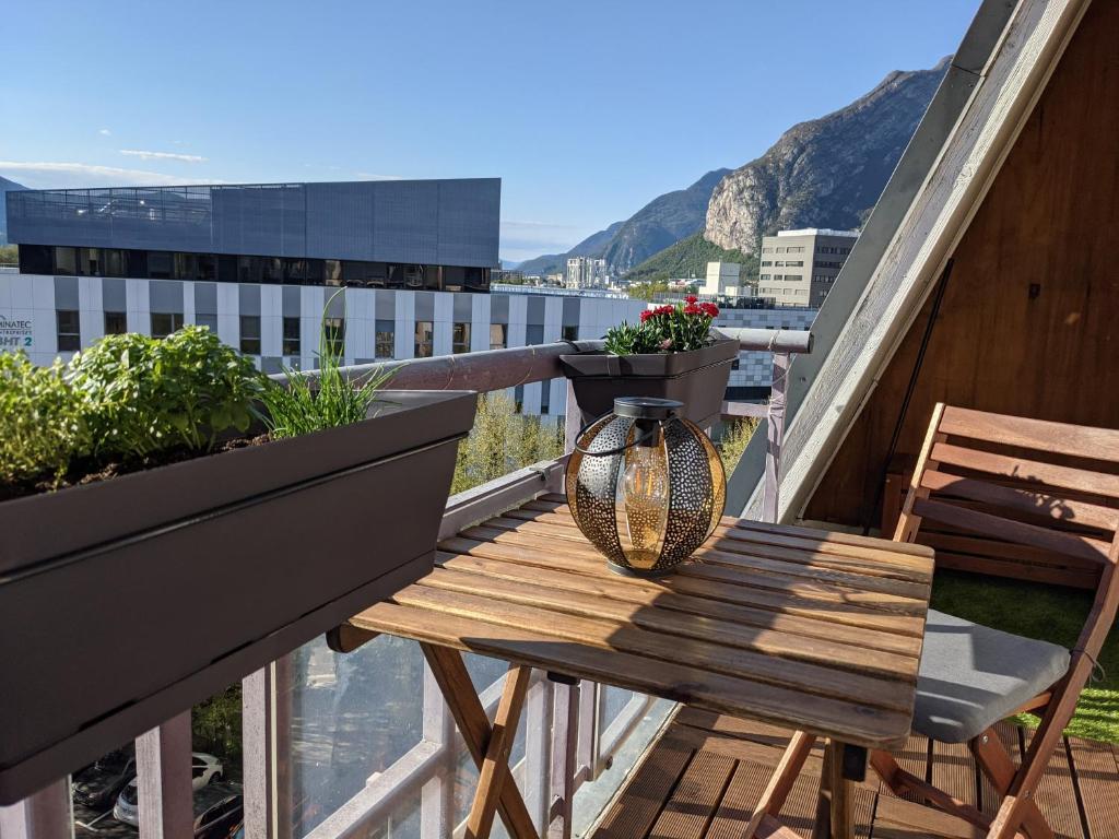 - une table en bois sur un balcon avec des plantes dans l'établissement Agréable T2 dernier étage avec balcon & parking - Grenoble Europole, à Grenoble