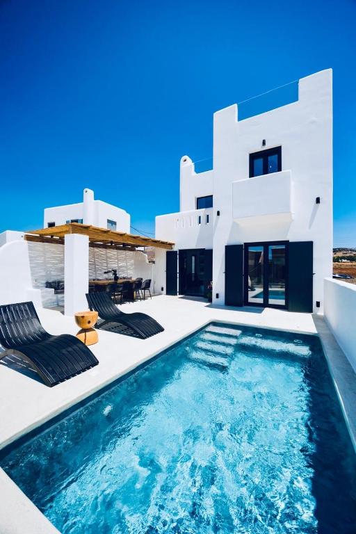 a villa with a swimming pool in front of a house at VotsaLo sea view house in Kastraki