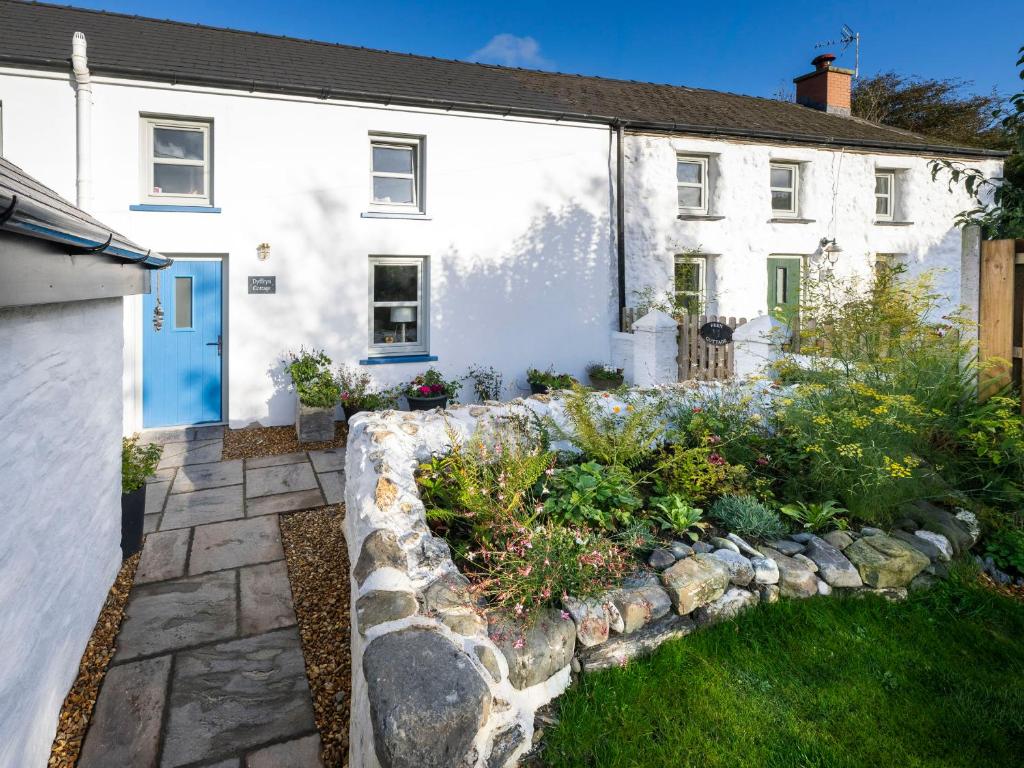 a white house with a garden in front of it at Dyffryn Cottage in Cardigan