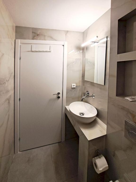 łazienka z toaletą, umywalką i drzwiami w obiekcie Hotel Tassos-Despina w mieście Pefkochori