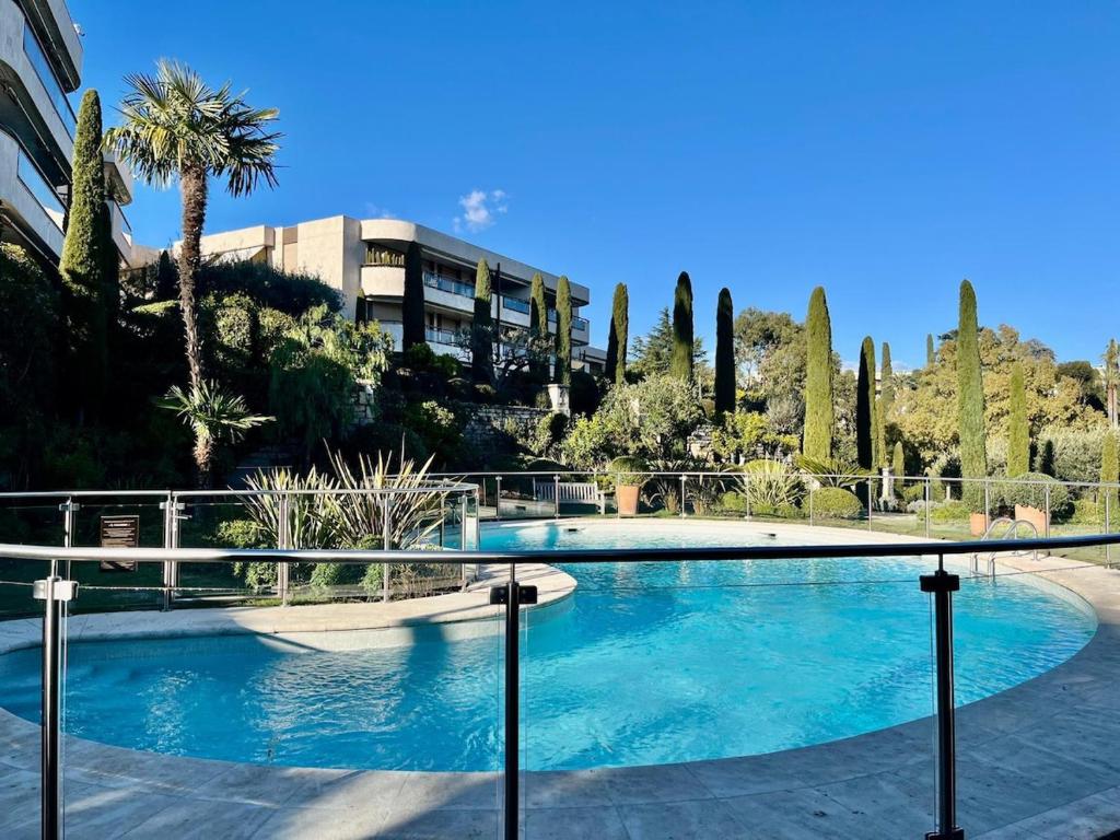 une grande piscine avec des arbres et un bâtiment dans l'établissement Beausite YourHostHelper, à Cannes