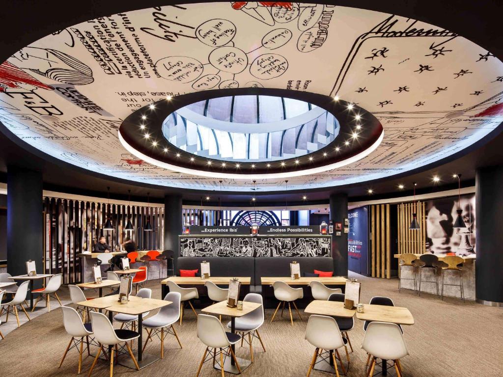 a restaurant with tables and chairs and a large ceiling at ibis Birmingham Centre New Street Station Hotel in Birmingham