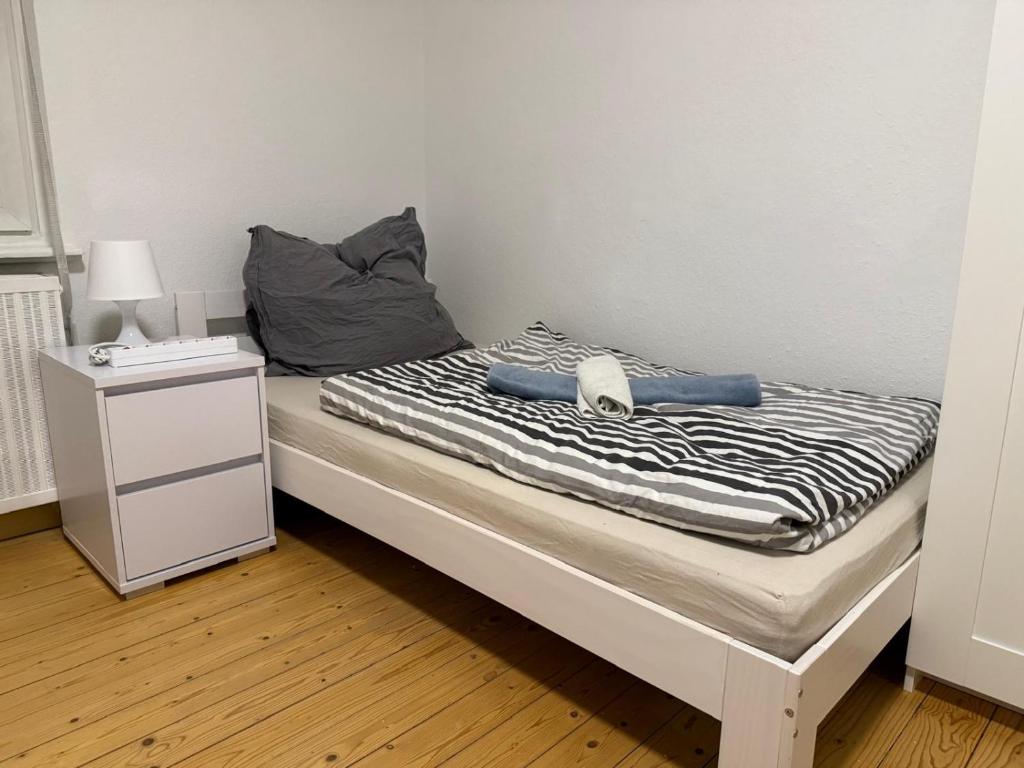 a bed with a black and white striped blanket and a night stand at Monteur- und Ferienwohnung Landau - Südliche Weinstraße in Landau in der Pfalz