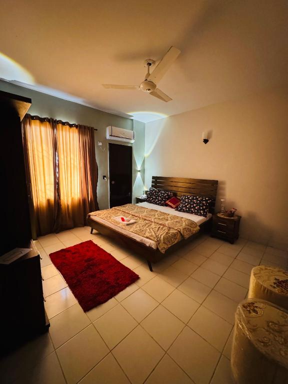 - une chambre avec un lit et un tapis rouge dans l'établissement Rosewood Cottage, à Karachi
