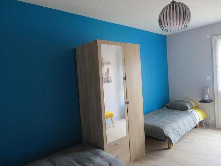 Cette chambre comprend 2 lits et un mur bleu. dans l'établissement Ti Marie Thérèse, à Fouesnant