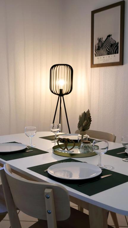 une table à manger avec une lampe, des assiettes et des verres dans l'établissement Les Nids de Montluçon, à Montluçon