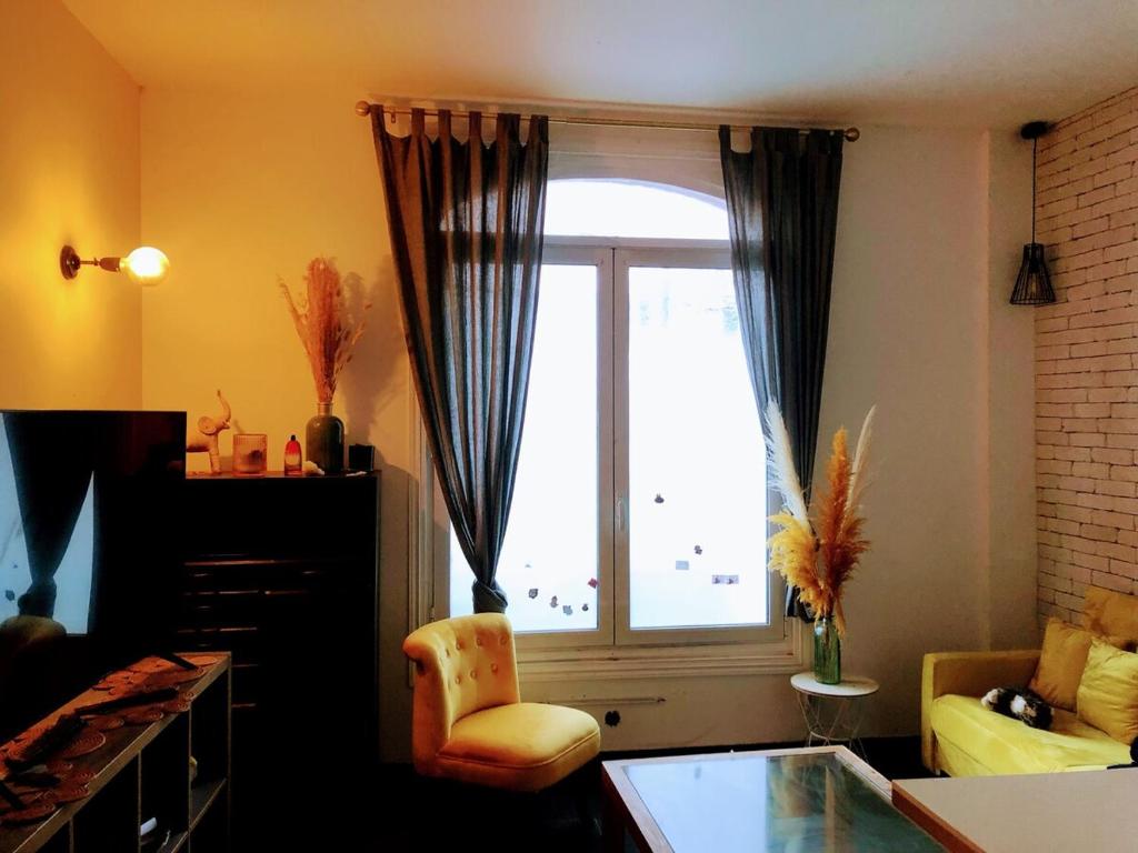 a living room with a large window and a chair at Appartement avec 2 chambres - Métro 8 Ecole Veterinaire in Maisons-Alfort