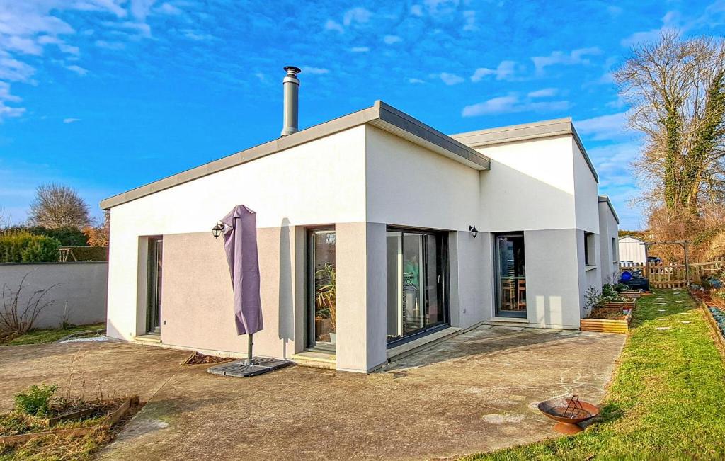 a white house with a purple umbrella in front of it at 3 Bedroom Nice Home In Amfreville in Amfréville