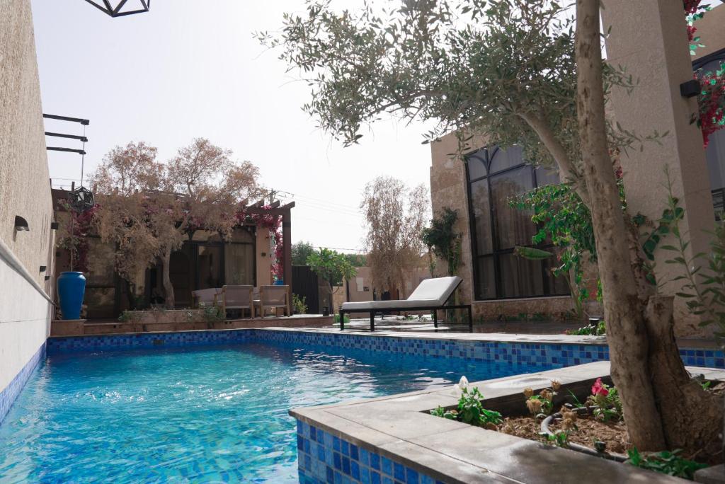 a swimming pool with a tree next to a building at Voyage Itlalat Resort منتجع وشاليهات فوياج اطلالات in Al ‘Uyaynah