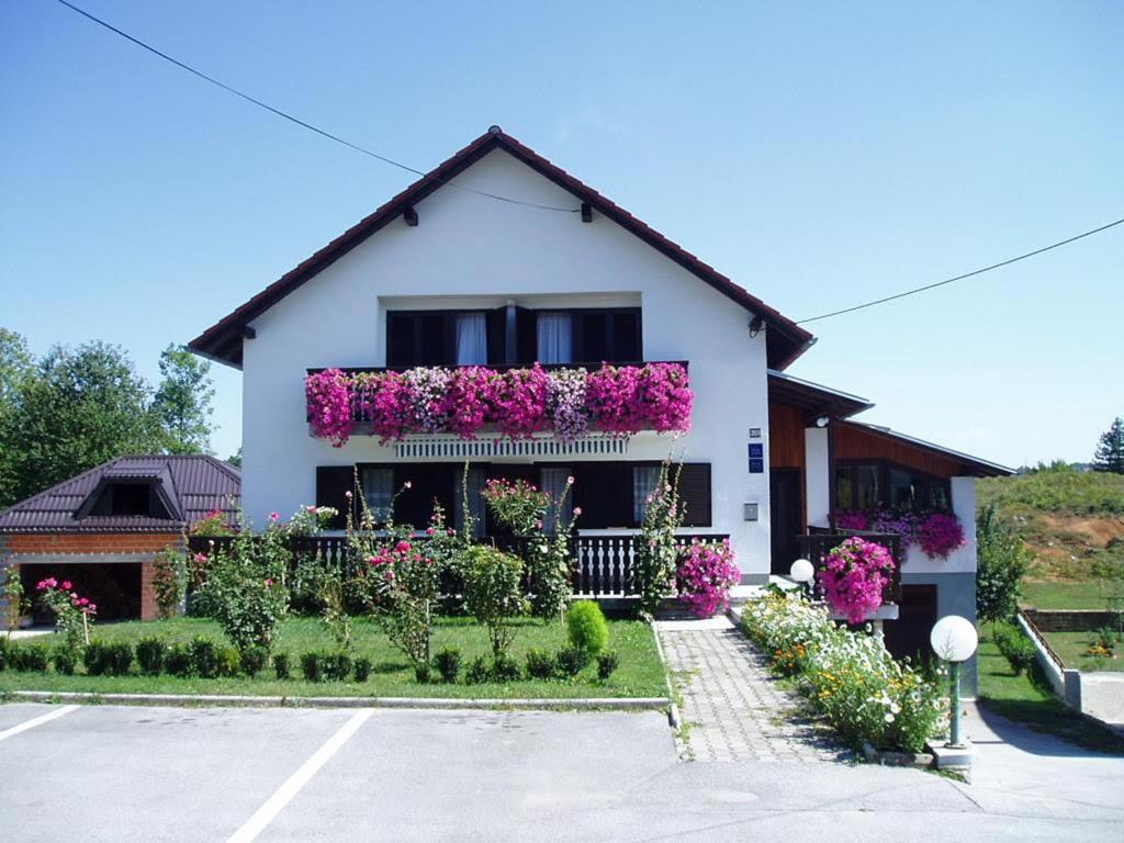 a white house with flowers on the side of it at Guest House Borić in Grabovac