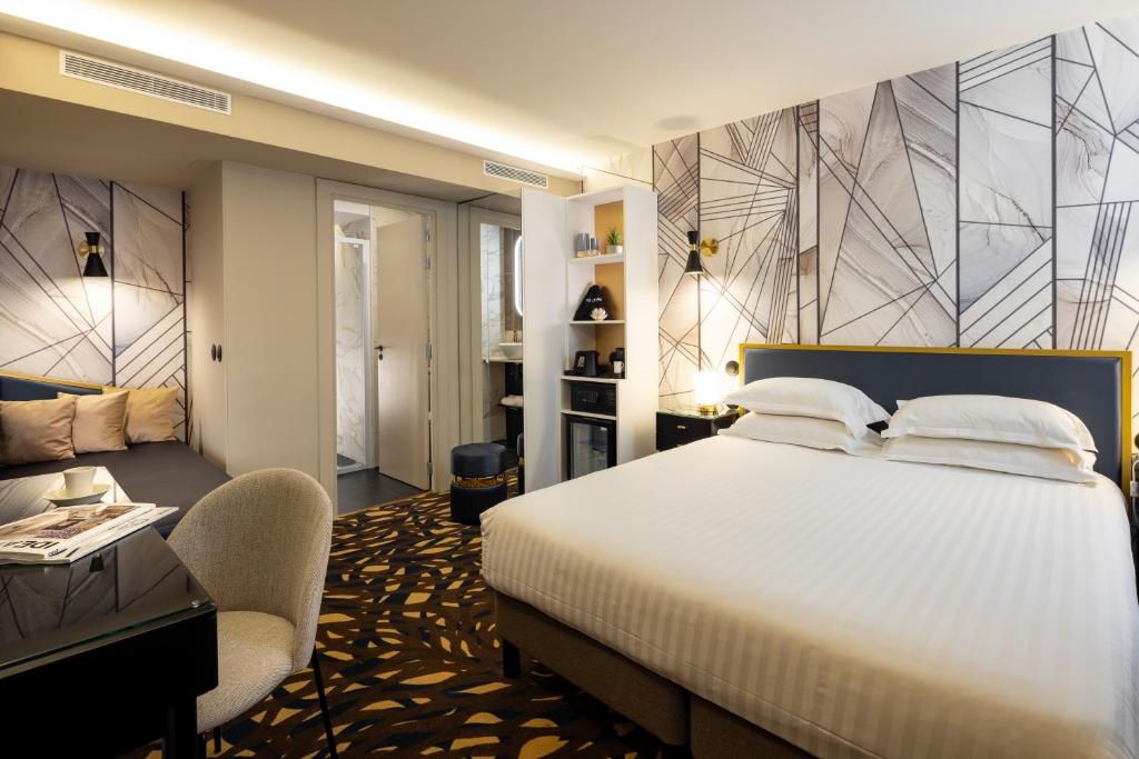 a bedroom with a bed and a desk and a chair at Hôtel Mondial in Paris