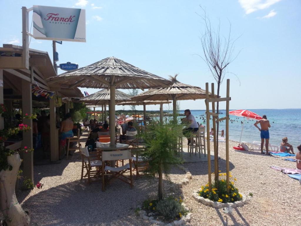 un grupo de personas sentadas en un restaurante en la playa en Apartment Barbara, en Novalja