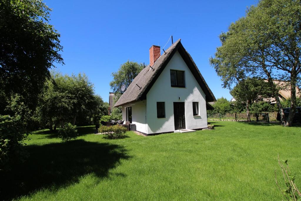 Cette petite maison blanche est dotée d'un toit de chaume. dans l'établissement Reethaus Ostseestrand 15, à Dierhagen