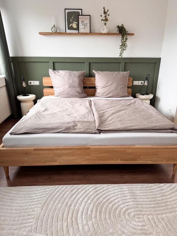 a bedroom with a large wooden bed with two pillows at TRIMOSA - Apartments & Homes in Bitburg