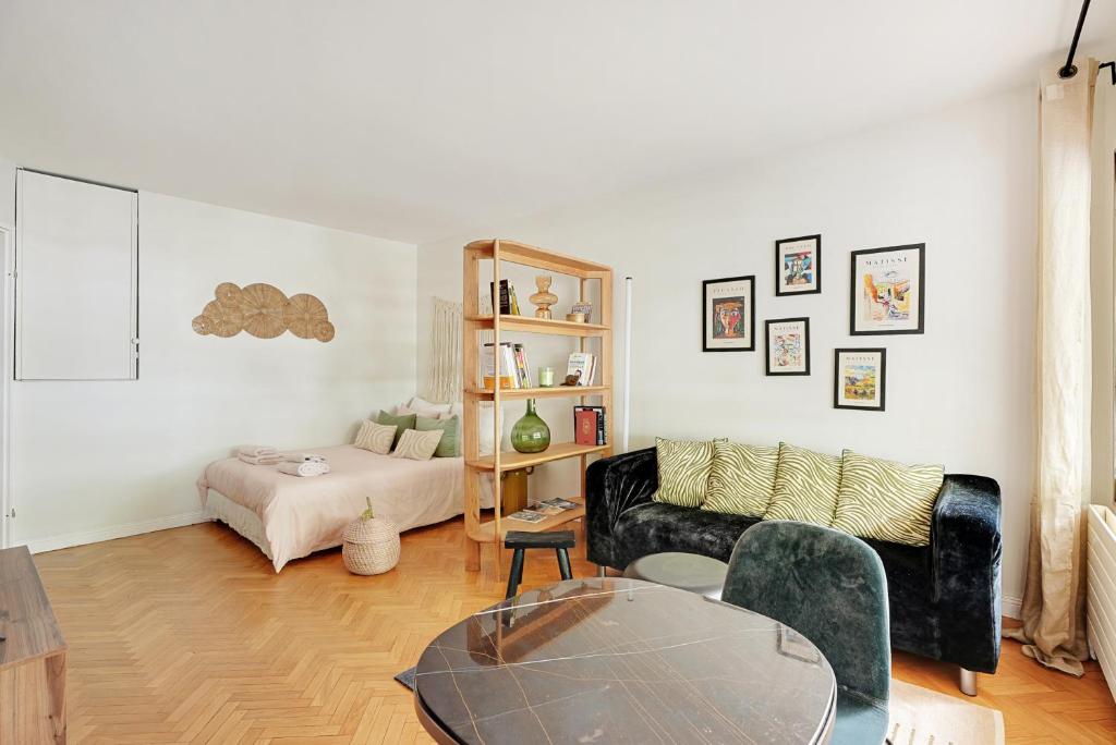 un salon avec un canapé noir et une table dans l'établissement Charmant studio 30 m2 proche Hôpital américain, à Levallois-Perret
